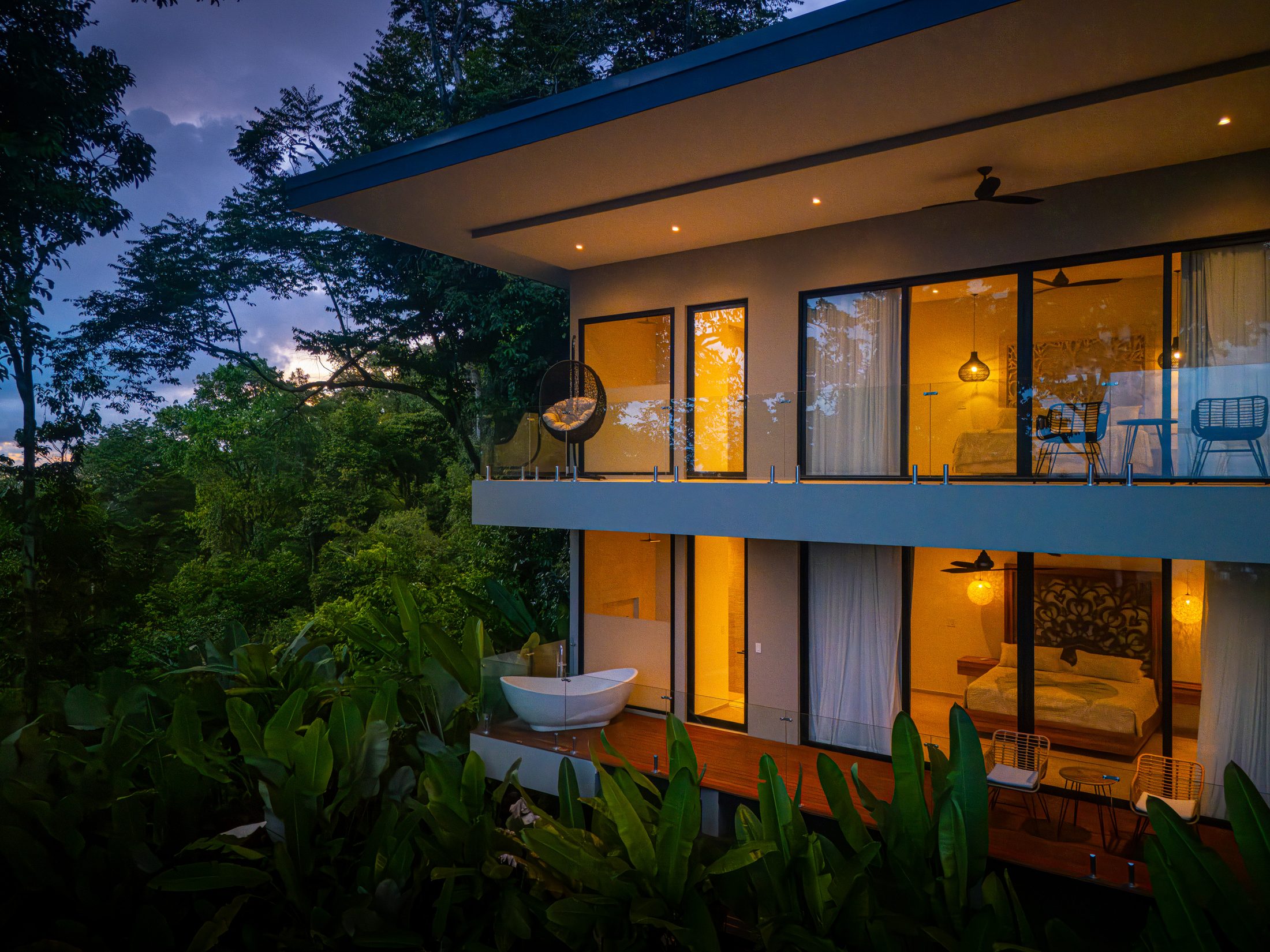 The residence illuminated at dusk above the jungle
